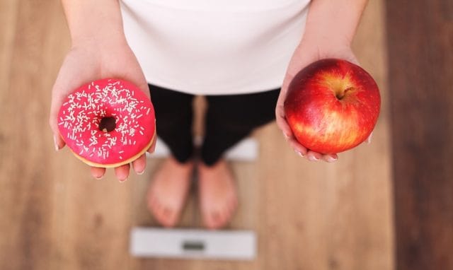 Woman weighing a donut vs an apple