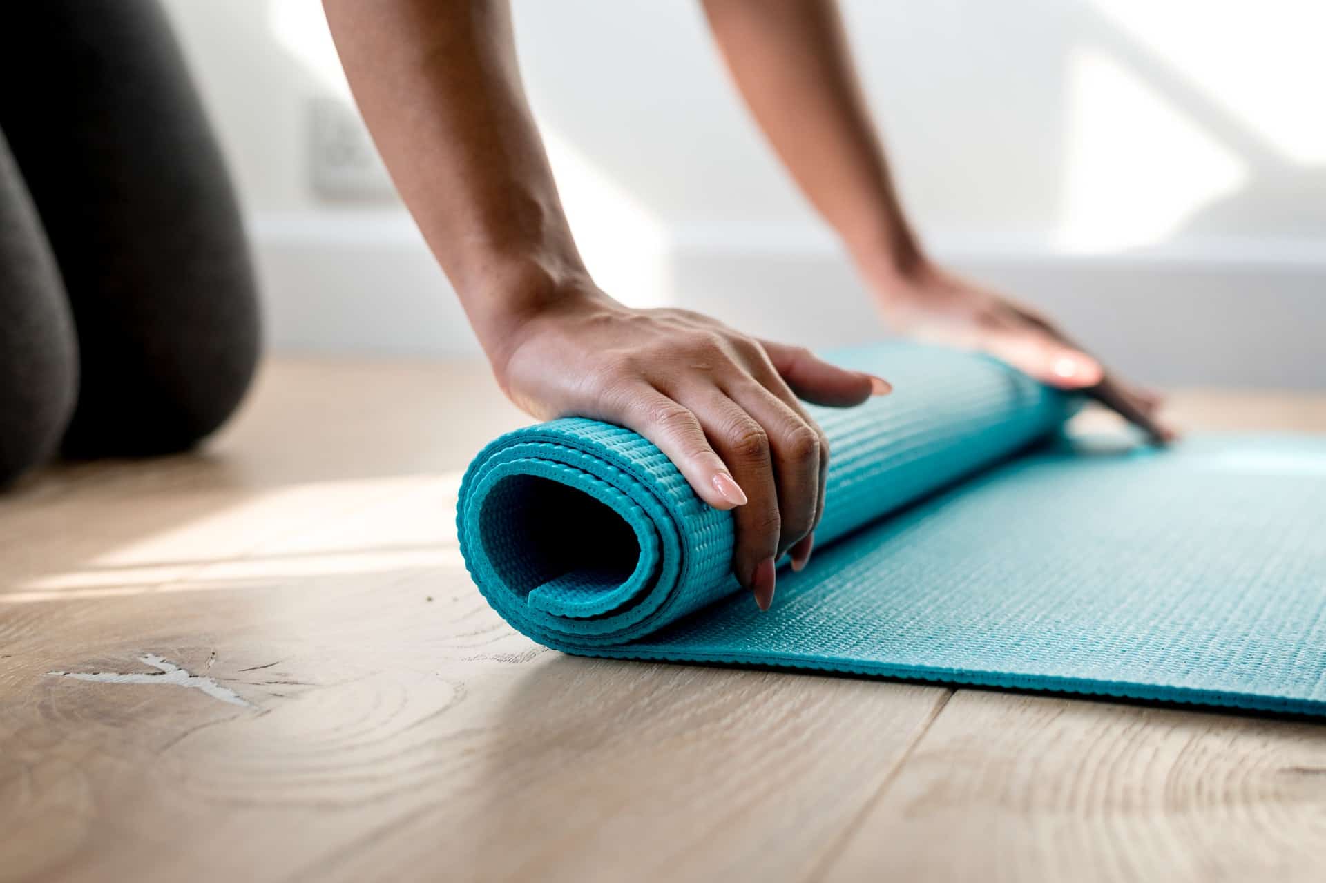 Hands rolling up a yoga mat.