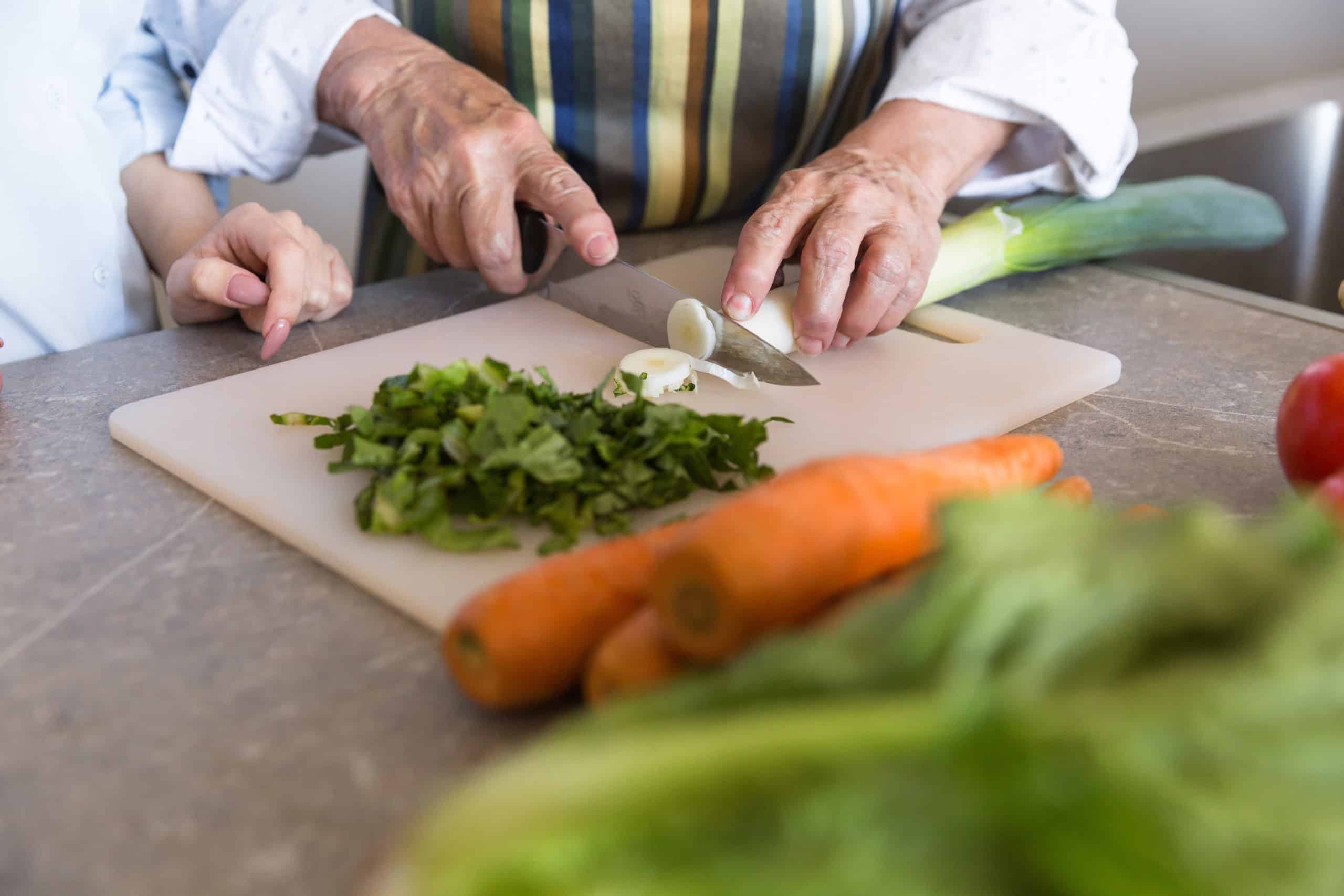 Older hands cutting vegetables