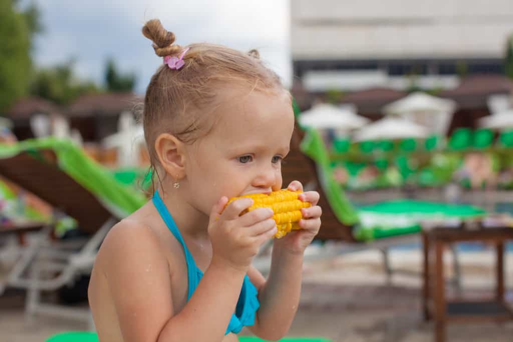 girl eating corn at the pool