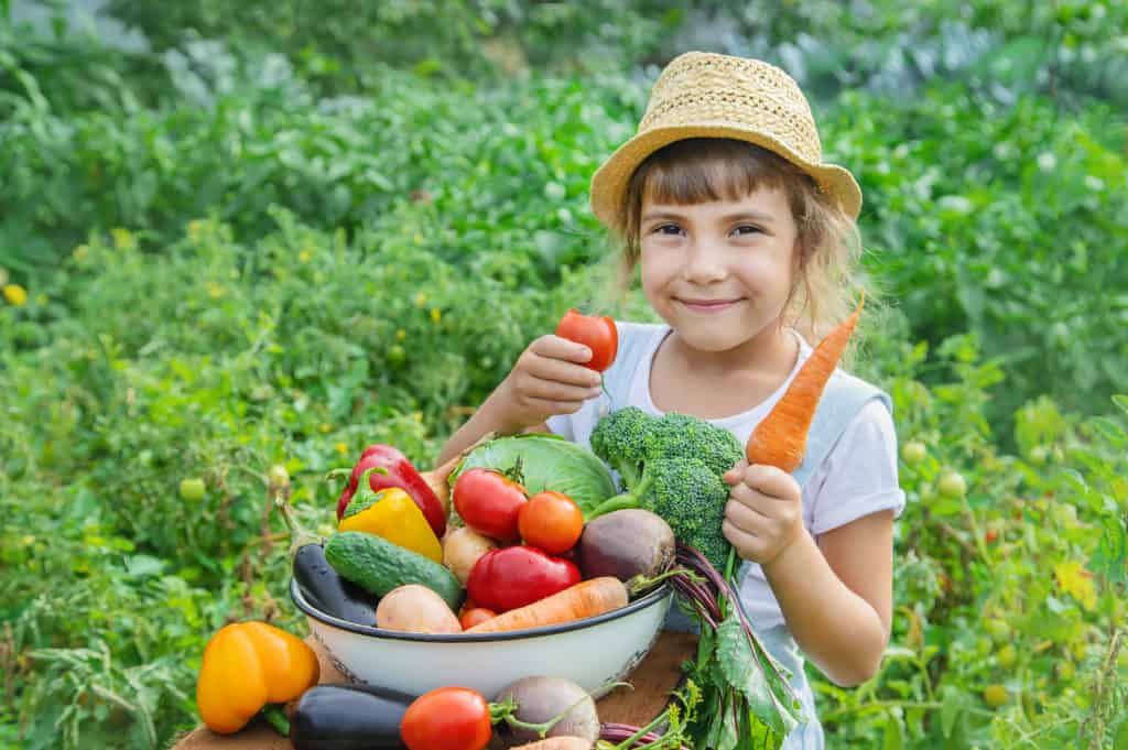 Child smiling and holding vegetables