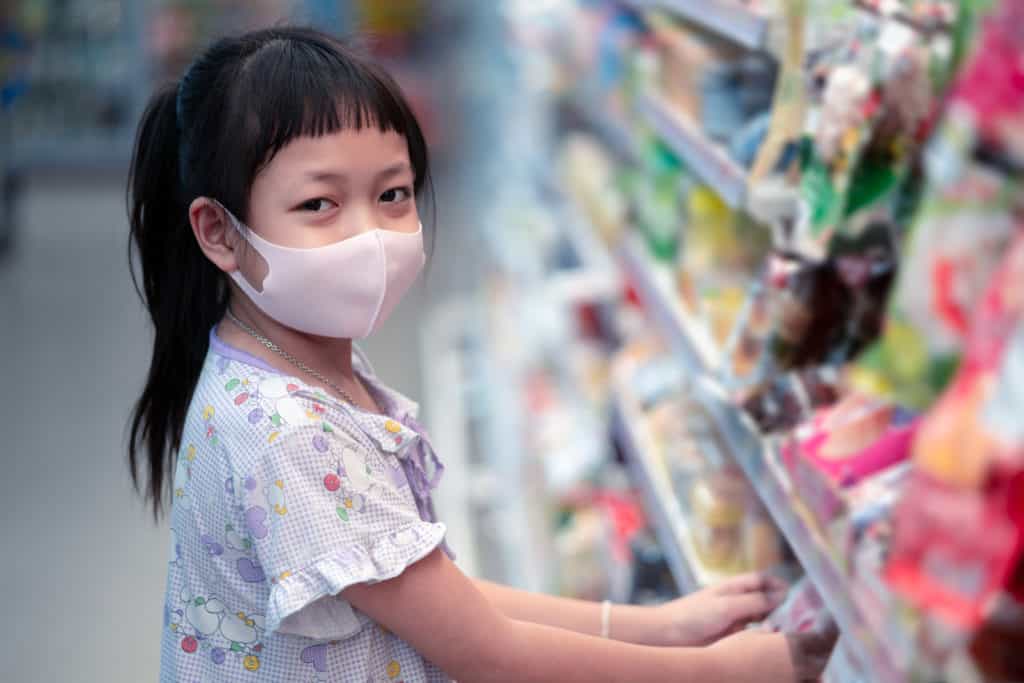 Young girl wearing mask in a grocery store.