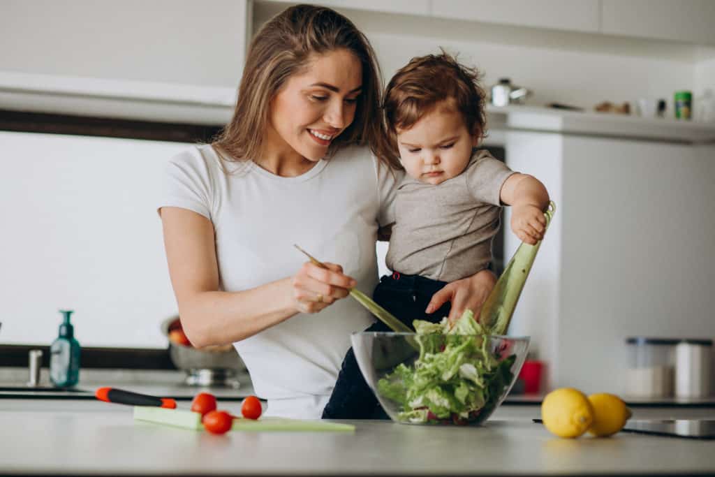 Mother and baby tossing salad together