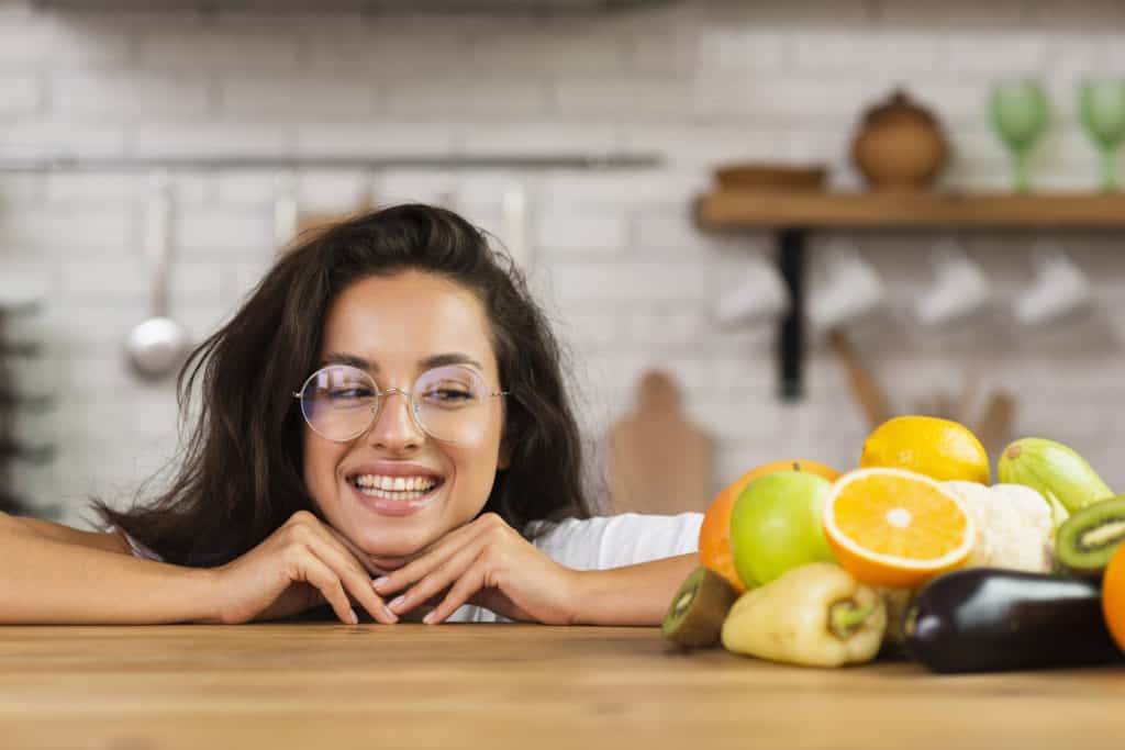 Close up of a smiling woman in a kitchen looking at fruits