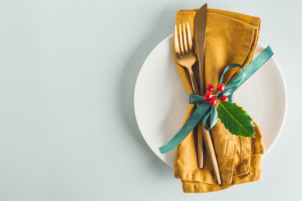 A placesetting with holiday bow around napkins and cutlery